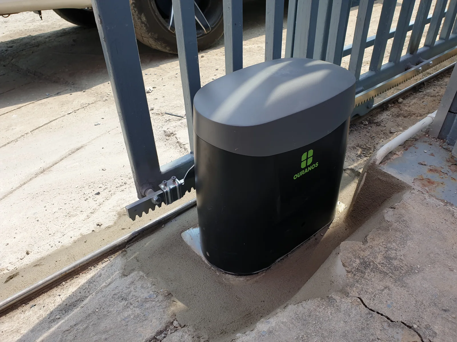 Ouranos A3 motor installed on a concrete base beside a sliding gate, rack fitted